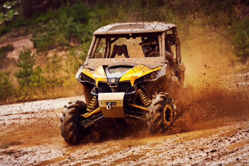 A UTV driver steers their vehicle through a muddy course