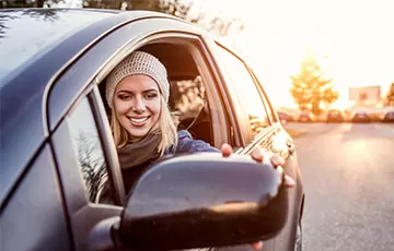 A female driver looks at herself in the side mirror of her vehicle.