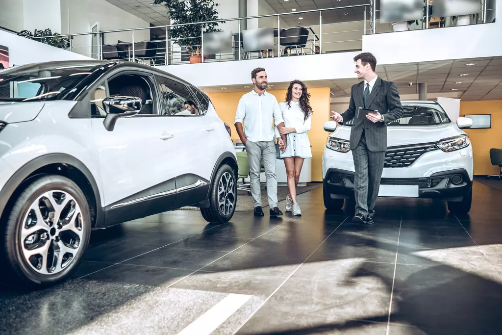 A car dealer shows a couple a vehicle they are thinking about financing with a credit union new auto loan.