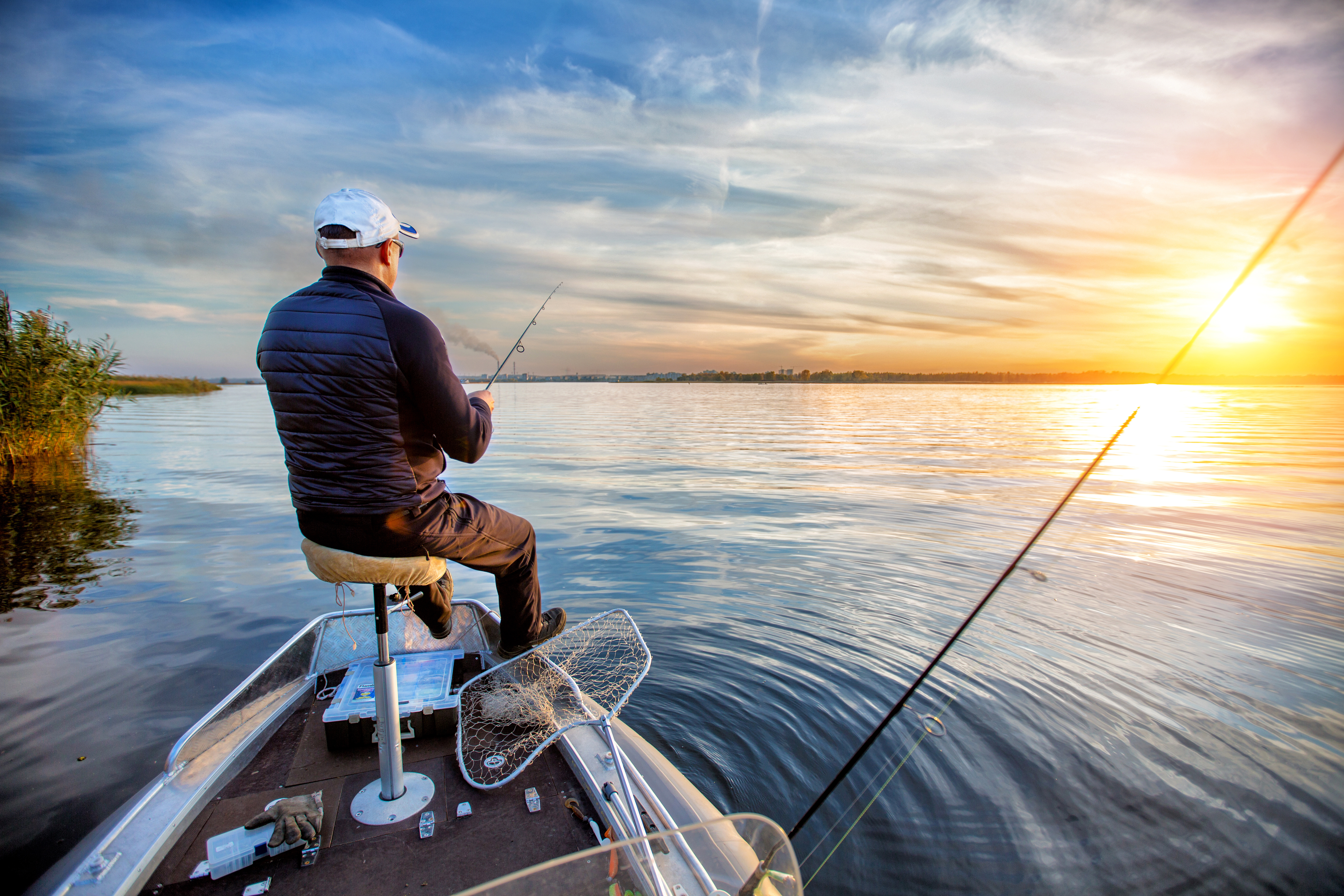 A man is fishing on the boat he bought with an OUCU Financial boat loan.