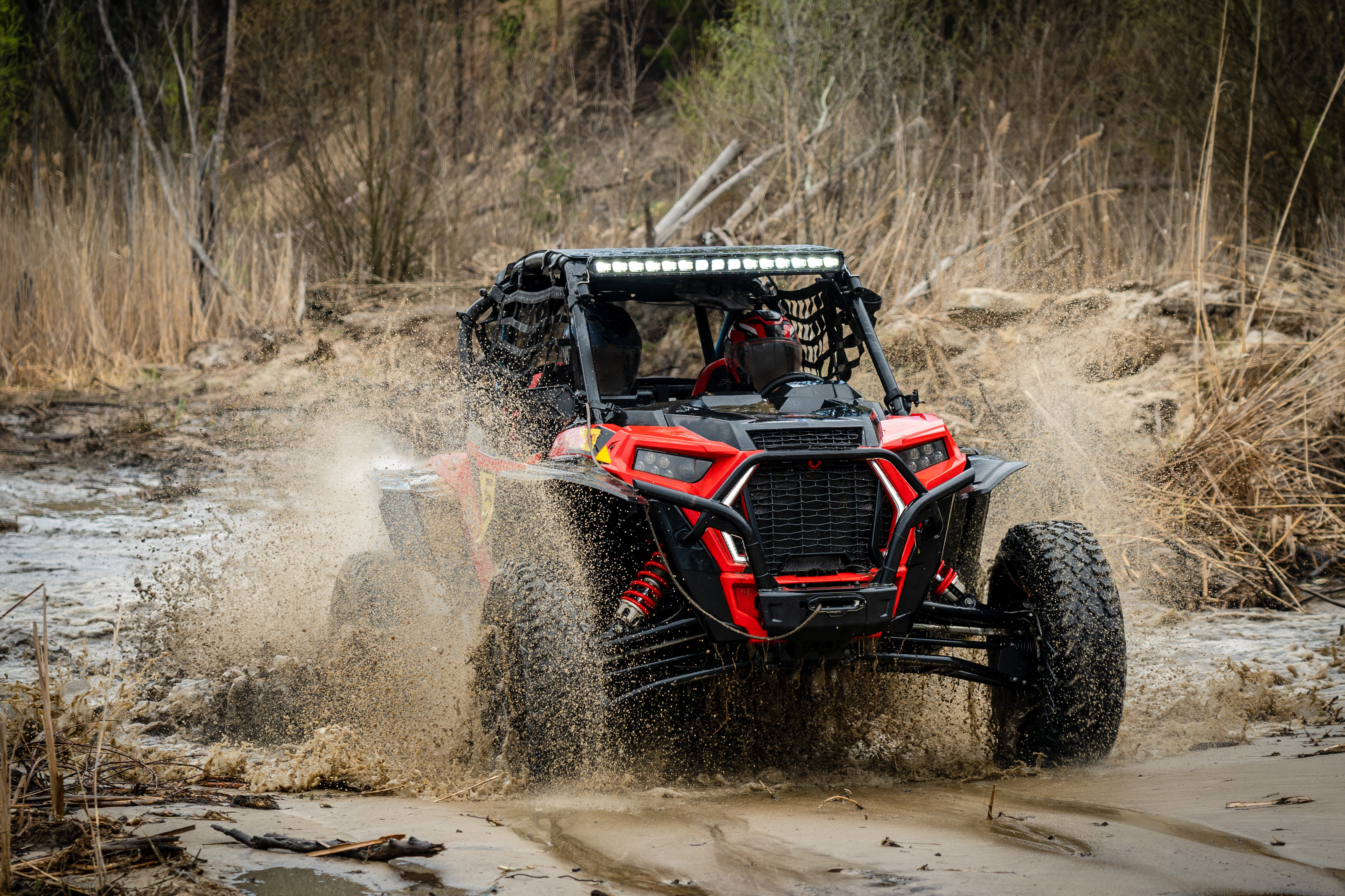 A man splashes through muddy waters in an all-terrain vehicle he financed with a credit union ATV loan.