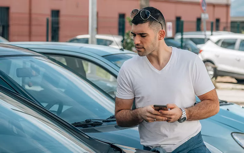 A man in a t-shirt checking out a car at the used car lot